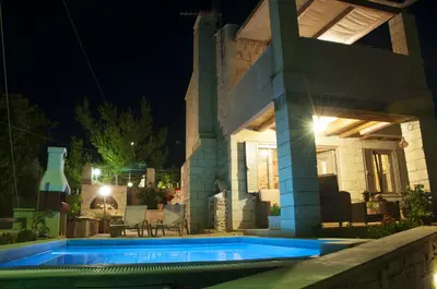 a swimming pool in front of a house at night at Pantanassa Villas in Agia Marina Nea Kydonias