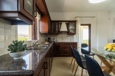 a kitchen with wooden cabinets and a table with chairs at Villa Aetheria by PosarelliVillas in Plátanos