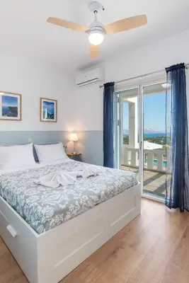 a white bedroom with a bed and a balcony at Villa Helissie in Vamos