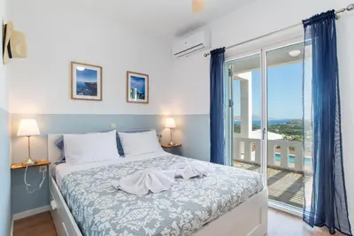 a bedroom with a bed with a view of a balcony at Villa Helissie in Vamos