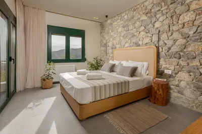 a bedroom with a large bed and a stone wall at Elirion Luxury Home II in Kamária