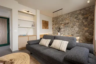 a living room with a gray couch and a stone wall at Elirion Luxury Home II in Kamária