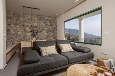 a living room with a couch and a stone wall at Elirion Luxury Home II in Kamária