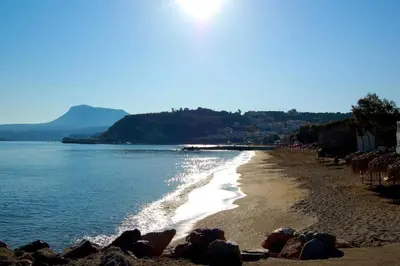 a beach with rocks and water and the sun at Irini Apartment I in Kalyves