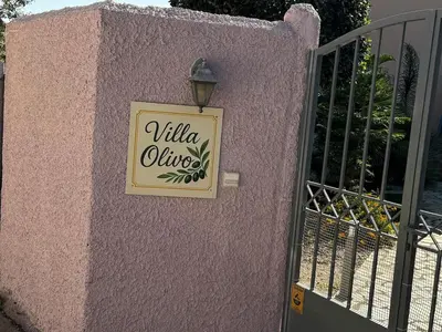 a sign on the side of a pink wall with a gate at Villa Olivo Kampani in CHQ