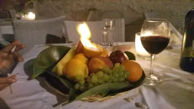 a bowl of fruit with a candle and a glass of wine at Paradise in Áyios Andhréas