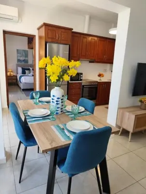a dining room table with blue chairs and yellow flowers at GreenView Chania Center Luxury Suite in Chania Town