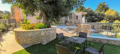 a patio with chairs and a table and a tree at Achlades The Mountain Paradise Villas - Studio with pool! in Aletrouvárion