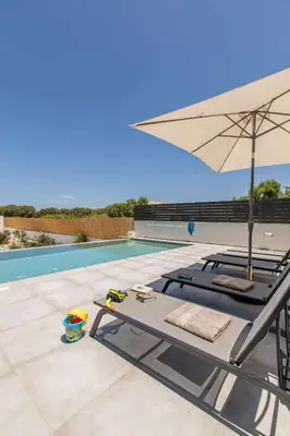 a lounge chair with an umbrella next to a swimming pool at Menta Villa by Vintage Travel in Tavronitis