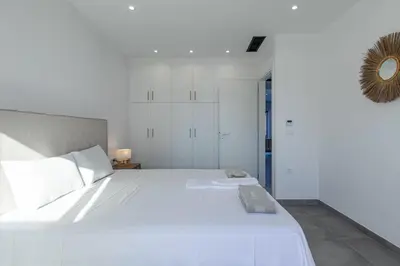 a white bedroom with a large white bed and a mirror at Myrtle Villa by Vintage Travel in Tavronitis