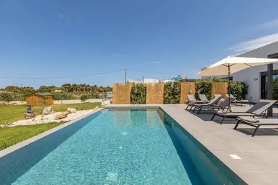 a swimming pool with two chairs and an umbrella at Myrtle Villa by Vintage Travel in Tavronitis