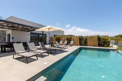 a swimming pool with chairs and a table and an umbrella at Diktamos Villa by Vintage Travel in Tavronitis