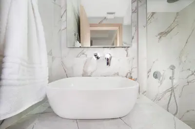 a white bathroom with a tub and a mirror at Didas Serenity Breeze in Kounoupidhianá