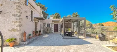 a house with a glass door on a patio at Achlades The Mountain Paradise Villas - Suite with a Private Jacuzzi, Pool, and a Balcony with an Amazing View! in Aletrouvárion