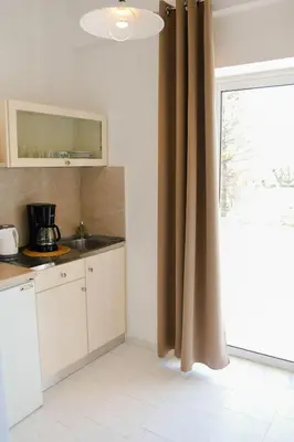 a kitchen with white cabinets and a window with a sink at Nik Litinas Apartments with pool in Plataniás