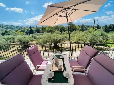 a patio with purple chairs and a table and an umbrella at Villa Domenico in Vryses