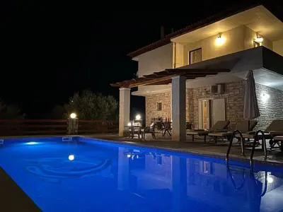a swimming pool in front of a house at night at Villa Domenico in Vryses