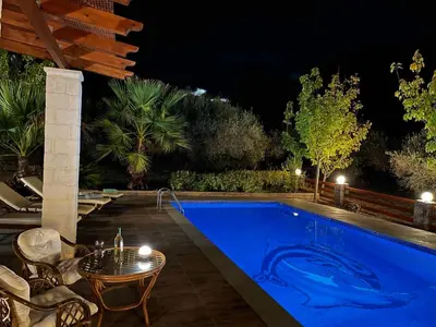 a swimming pool at night with a table and chairs at Villa Domenico in Vryses