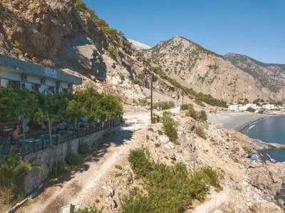 a building on the side of a mountain next to the ocean at Sweet Corner Masxali in Agia Roumeli