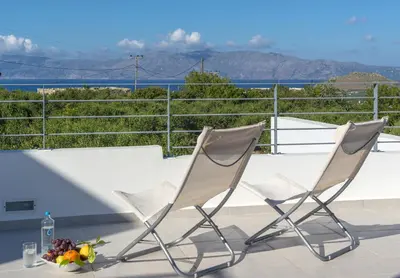 two chairs and a vase of flowers on a balcony at Gramvousa Villas in Kissamos