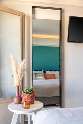 a mirror in a room with a bed and a table at Elia Bettolo Hotel in Chania Town