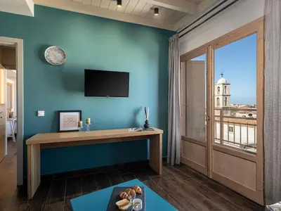 a room with a blue wall with a desk and a window at Elia Bettolo Hotel in Chania Town