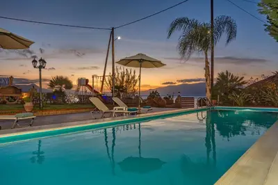 a swimming pool with a sunset in the background at Julia's Cosy Apt in Ravdhoúkha