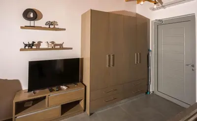 a living room with a flat screen tv on a wooden cabinet at Michalis-Nina studios in Livanianá