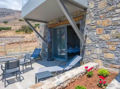 a patio with chairs and tables and a stone wall at Michalis-Nina studios in Livanianá