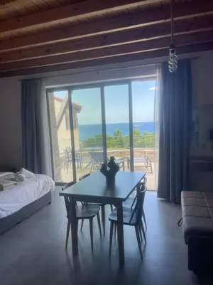 a bedroom with a table and a view of the ocean at Michalis-Nina studios in Livanianá