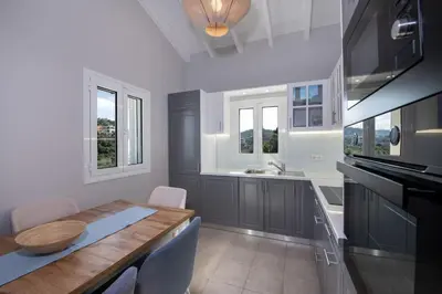 a kitchen with a wooden table and some windows at Villa Mareli - Beachside Villa with Heated Pool in Almirida