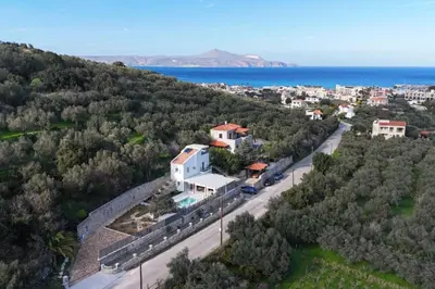 an aerial view of a house on a hill next to the ocean at Villa Mareli - Beachside Villa with Heated Pool in Almirida