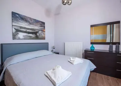 a bedroom with a bed and a picture of a boat at Marilia by Vintage Travel in Maleme