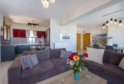 a living room with a brown couch and a kitchen at Marilia by Vintage Travel in Maleme