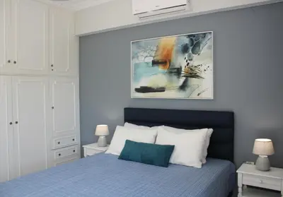 a bedroom with a blue bed and a painting on the wall at Nerina Home Chania in Chania Town