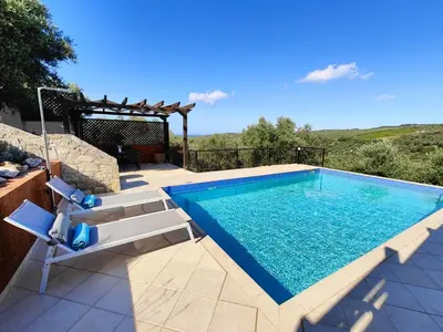 a swimming pool with two chairs and a table at Bellavista Panorama Darmarochori in Darmarochori