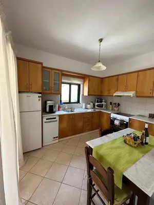 a kitchen with wooden cabinets and a table with a green table cloth at Villa Elpida Aspro in Koprána