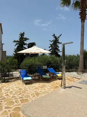 a patio with two chairs and a table and an umbrella at Villa Elpida Aspro in Koprána