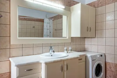 a bathroom with a sink and a washing machine at Sunlit sea view apartments in Stalos