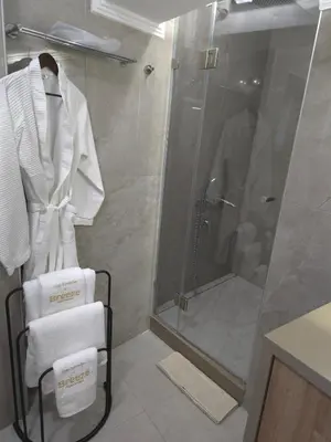 a bathroom with a shower and white towels on a rack at Breeze Apartment in Chania Town
