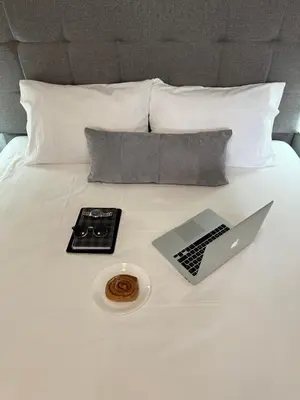 a laptop computer on a bed with a remote control at Dom Suites in Aghii Apostoli