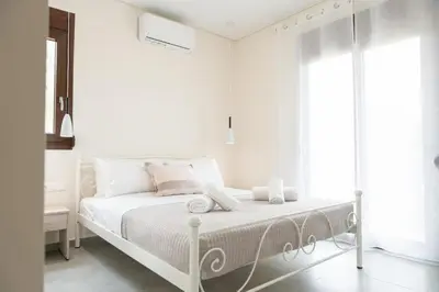 a white bedroom with a bed and a window at Terra Blue Suites - Nefeli in Kalyves