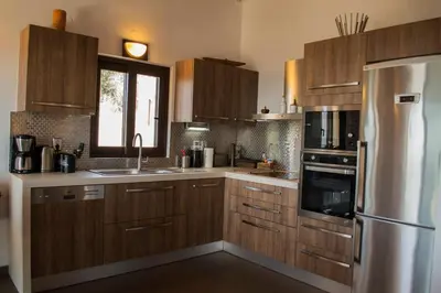 a kitchen with wooden cabinets and a stainless steel refrigerator at Villa Marie Homeleader in Delimanolianá
