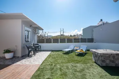 a patio with grass and two chairs and a table at Margie's Apartments in Kissamos