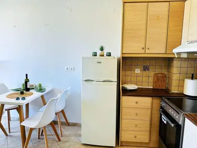 a kitchen with a white refrigerator and a table at Son of the Beach Apartment - 20sec walk to beach in Chania Town