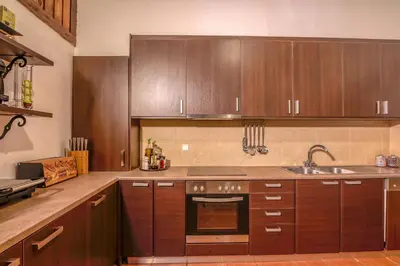 a kitchen with wooden cabinets and a sink at Villa Dimmare by PosarelliVillas in Kissamos
