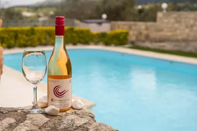 a bottle of wine and a glass next to a pool at Villa Faye by PosarelliVillas in Metókhion