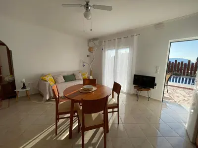 a living room with a table and a couch at Dans une villa avec piscine privée, calme, proche des plages, vues mer et montagnes in Tsivarás