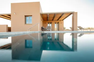 a villa with a swimming pool in front of a house at Giannoulis Ele Villas in Skoutelónas