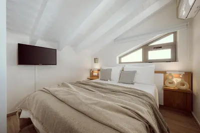 a bedroom with a bed with a tv on the wall at Ethereal White Villas in Gramvousá
